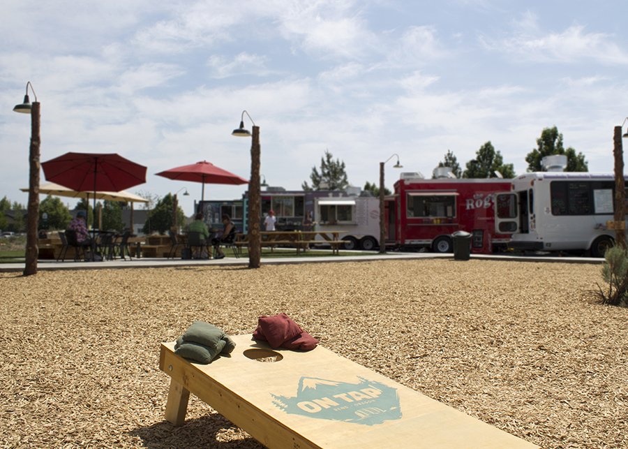 A large woodchip lined game area  and in the background several food trucks stand serving patrons
